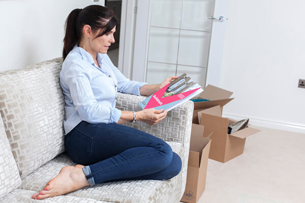 a woman curled up on the sofa in her new home reading the nhbc buildmark booklet