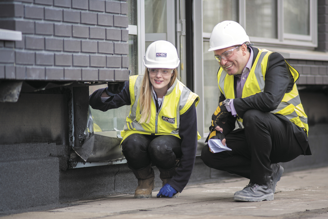 a photo of two people crouching on site in site safety clothing