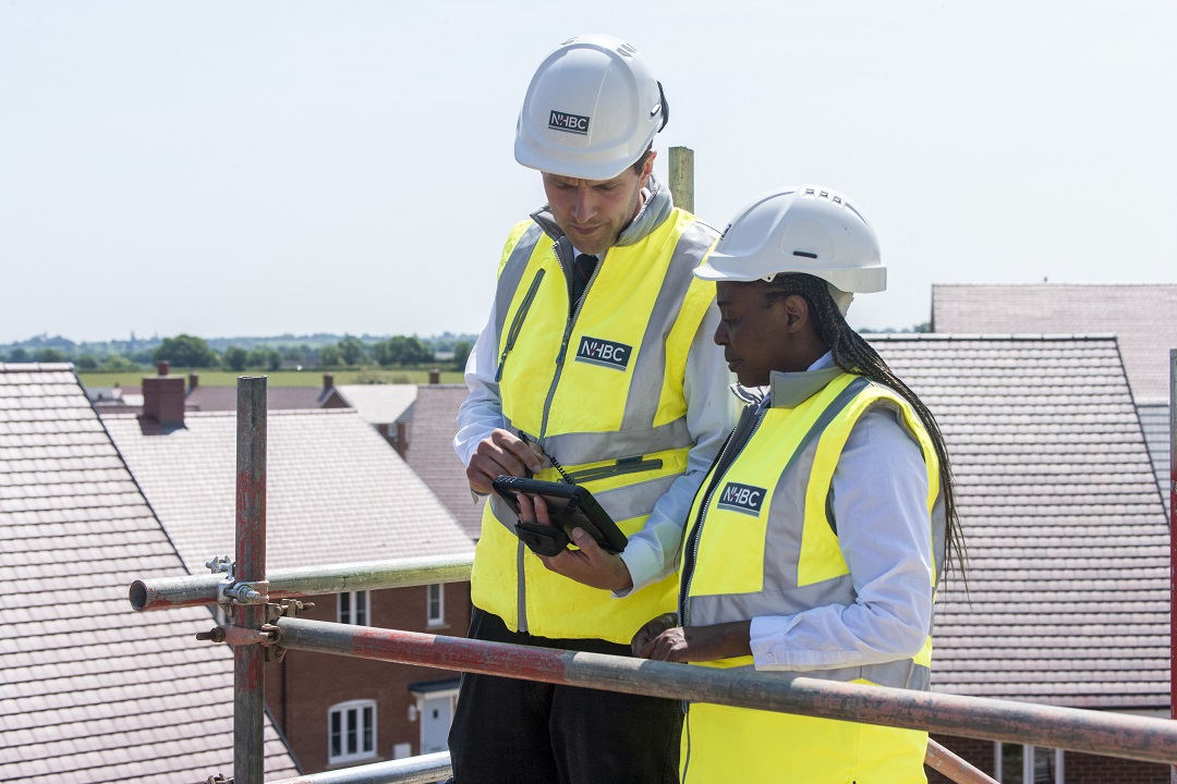 a photo of two people in site safety clothing looking at a document