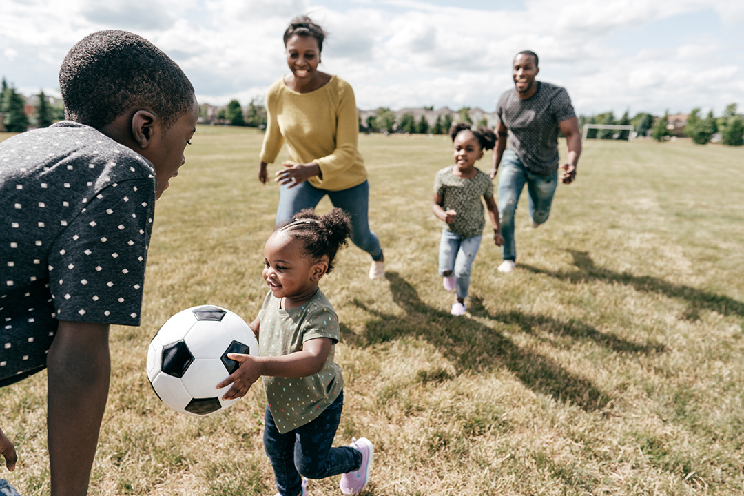 a family in a field playing with a football
