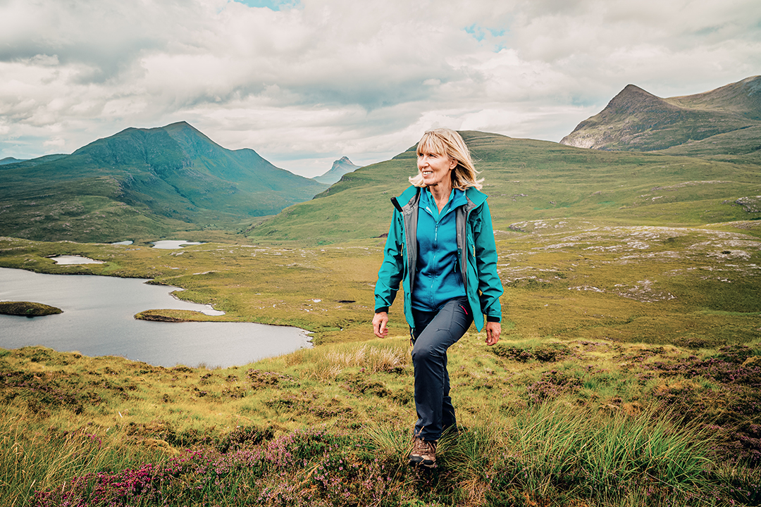 a woman in a blue jacket walking on a hillside