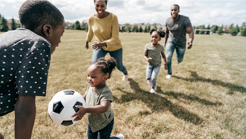 a family in a field happily playing football