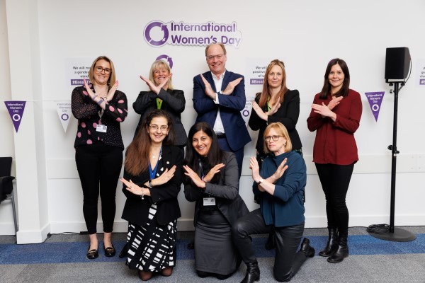 a group of people making shapes with their arms to celebrate international women's day
