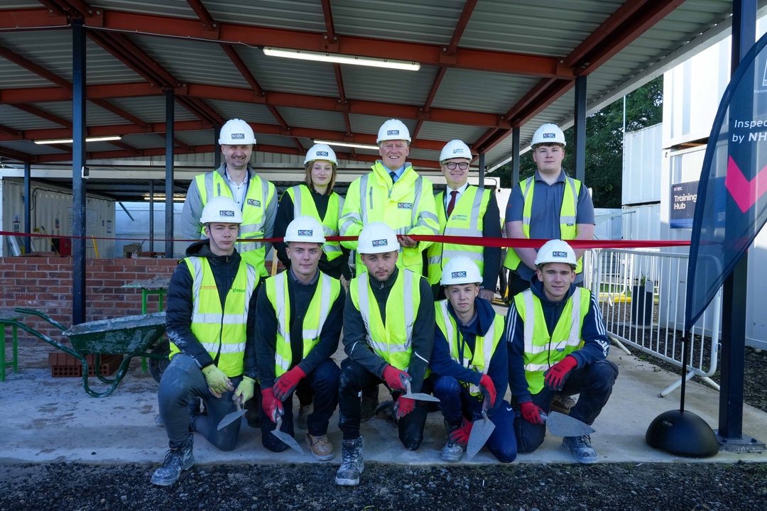 the bricklaying apprentice team in site safety clothing smiling at the camera
