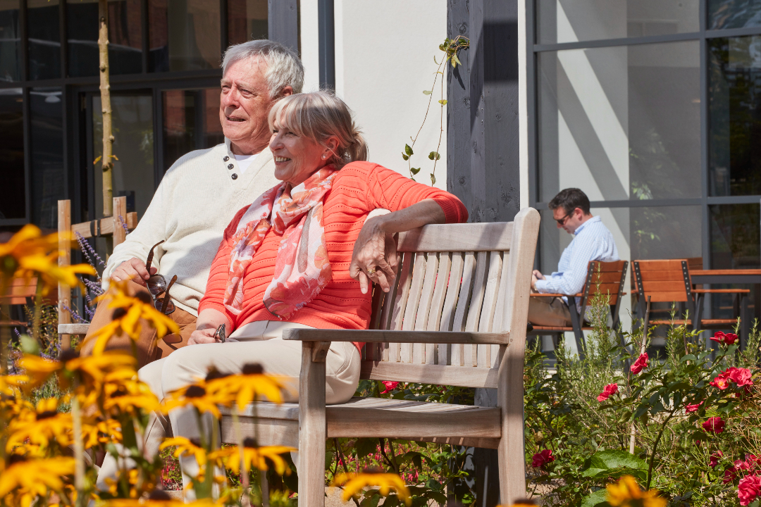 an older couple sitting on a bench in the sunshine