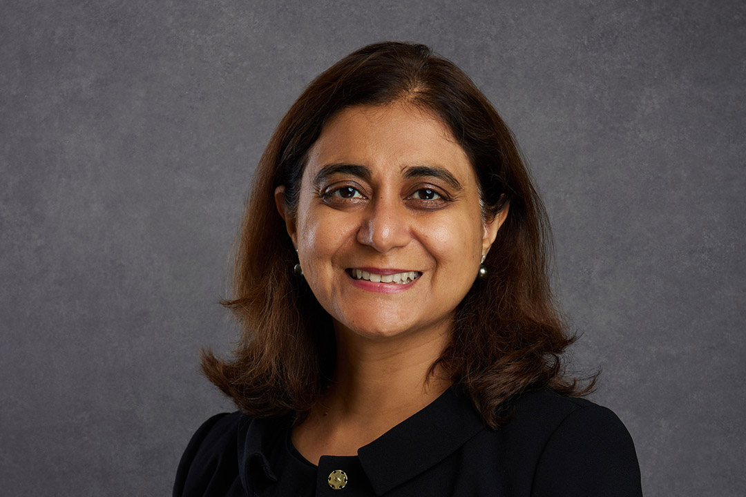 Tesula Mohindra, Non-executive Director of the Board of NHBC, smiling at the camera on a grey background