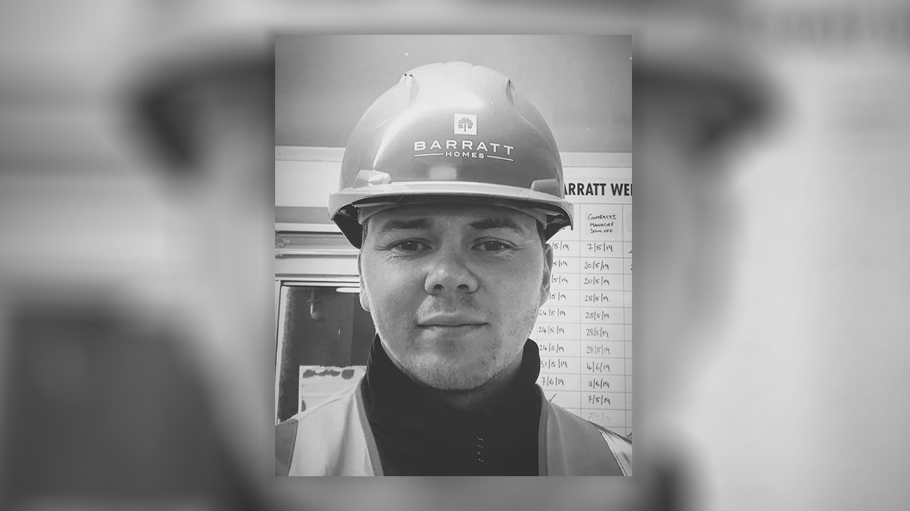 Craig McWilliams of Barratt Homes, in a hard hat, smiling at the camera in black and white