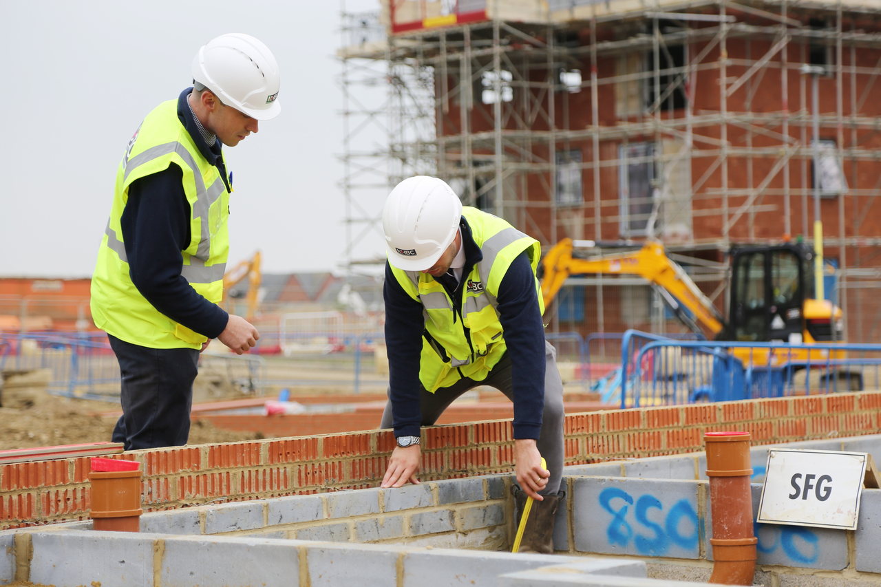 two people in site safety clothing investigating student brickwork