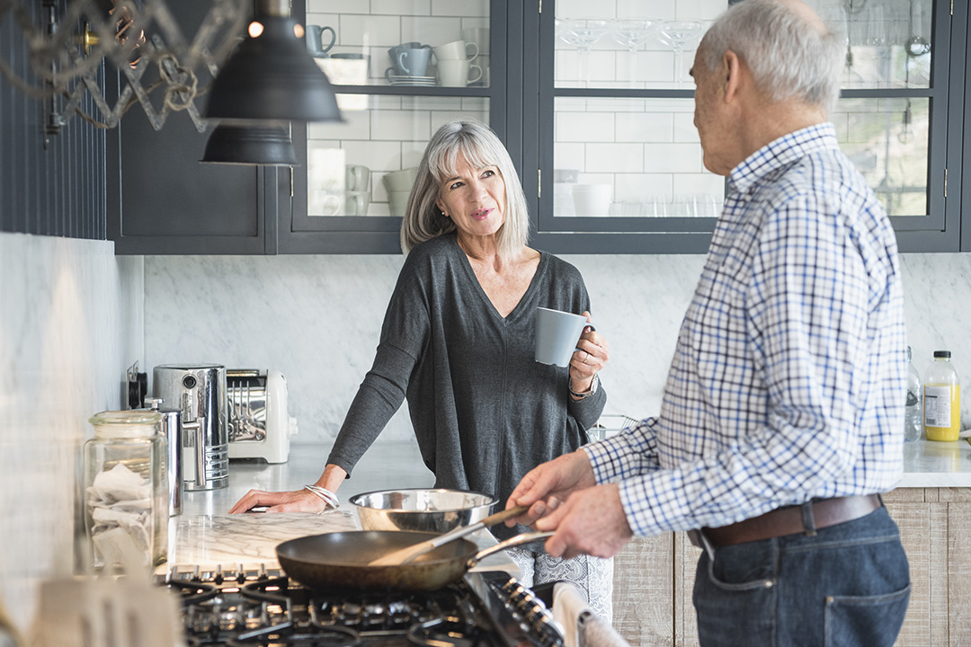 an older couple cooking and spending time together in the kitchen