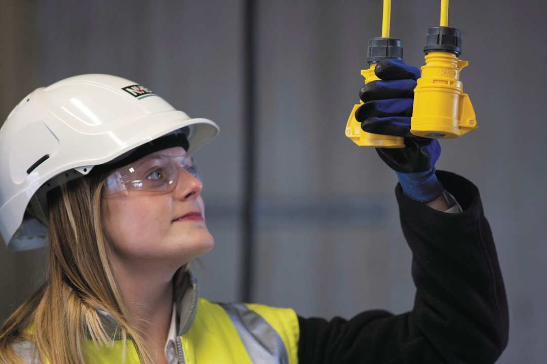 a woman on site, wearing a high vis vest and a hard hat, inspecting a pulley