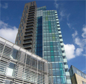 a modern, glass fronted skyscraper with a blue sky in the background