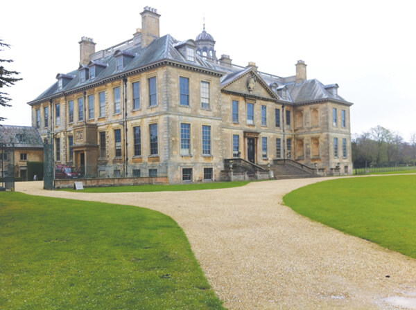 a photo of belton house from the outside, showing a beige manor house and large, sprawling gardens