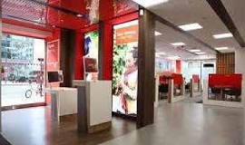 a photo of the inside of a branch of santander, with adverts and modern help stations