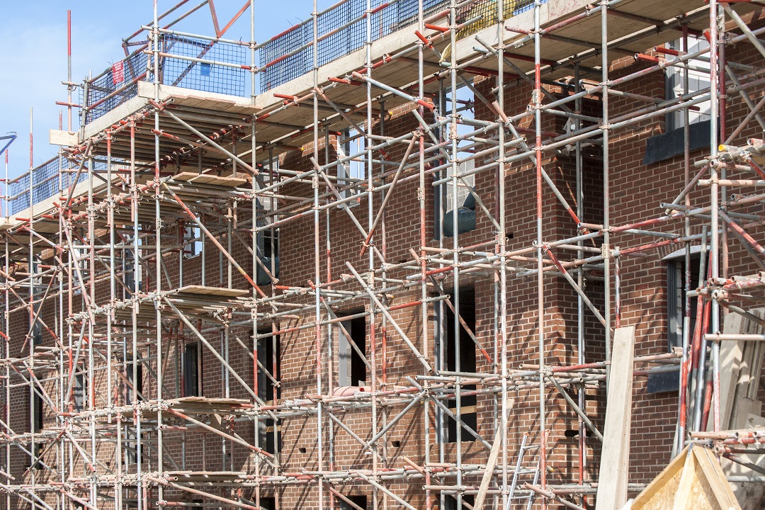 an image showing red-brick houses under construction surrounded by scaffolding