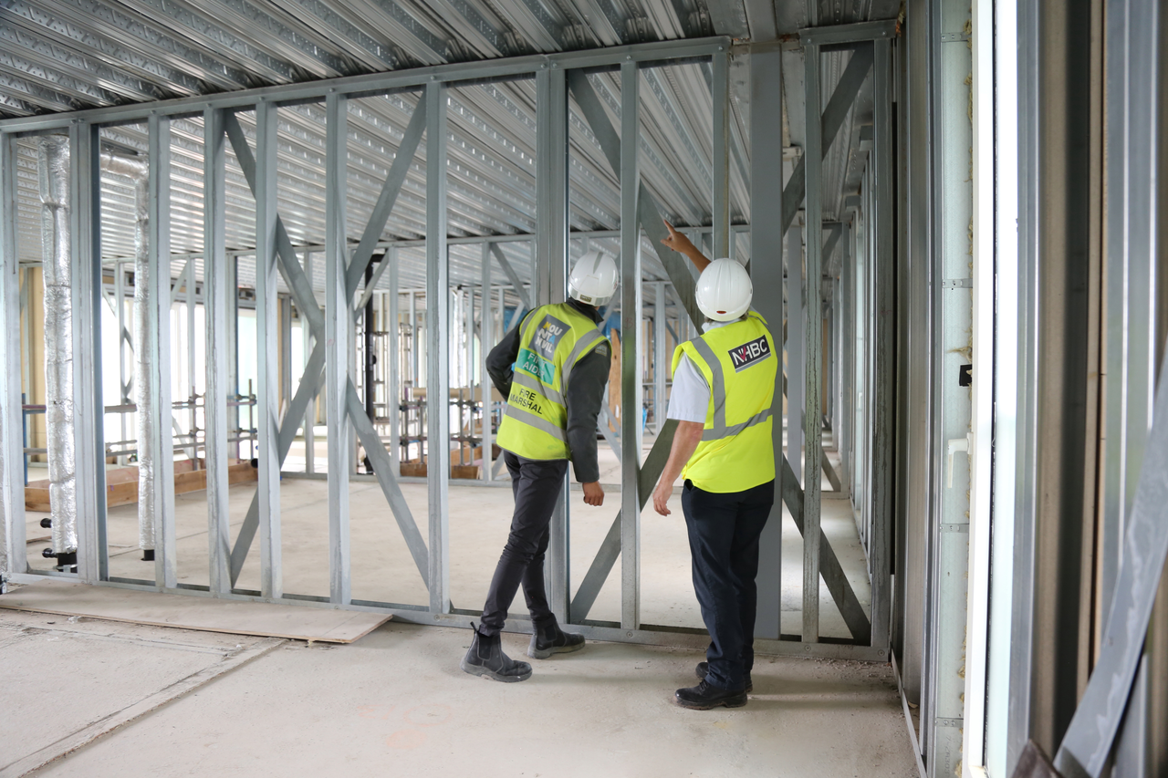 two people on site inspecting steel framework for a building