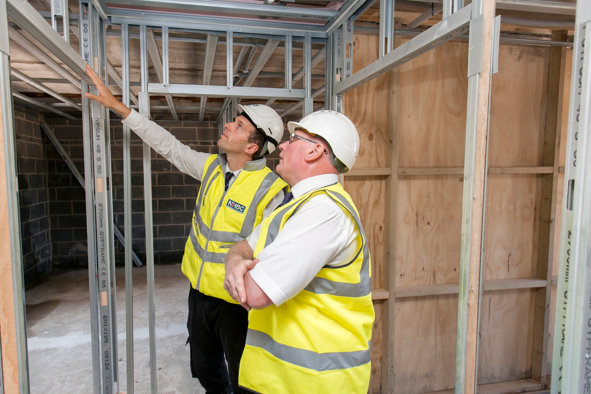 a photo of a builder and developer talking on site in site safety clothing