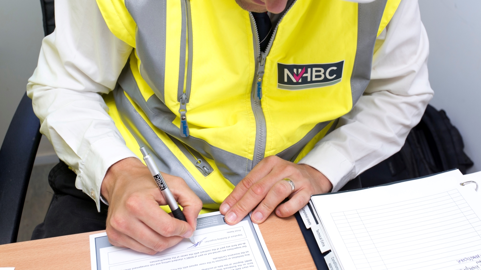 a person in a high vis vest signing a document