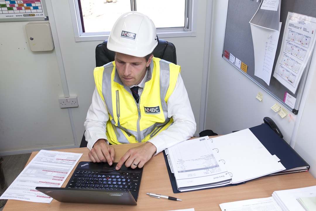 a person in a high vis vest an hard hat signing a document