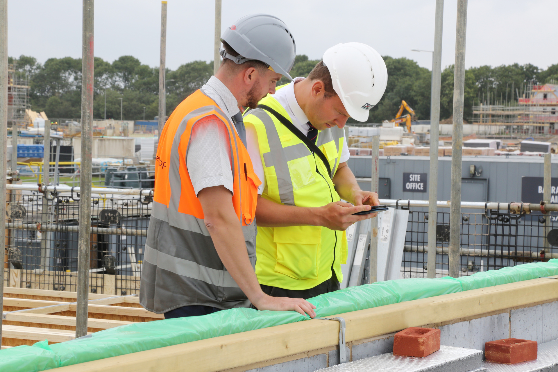 a photo of two builders talking on site in site safety clothing