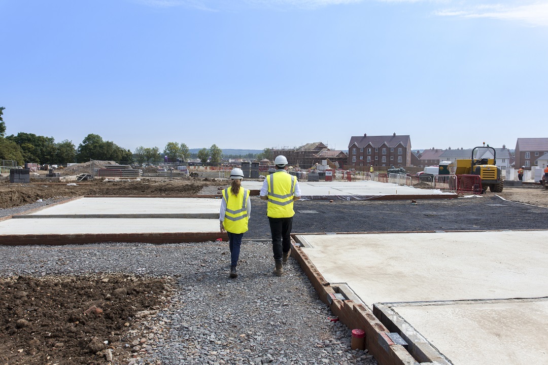 a photo of two people in site safety clothing walking on site