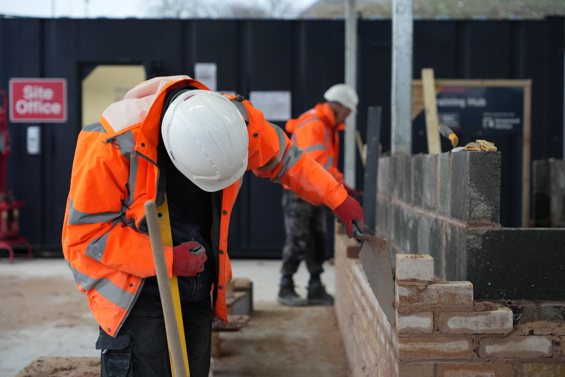 a photo of a bricklayer at work in site safety clothing