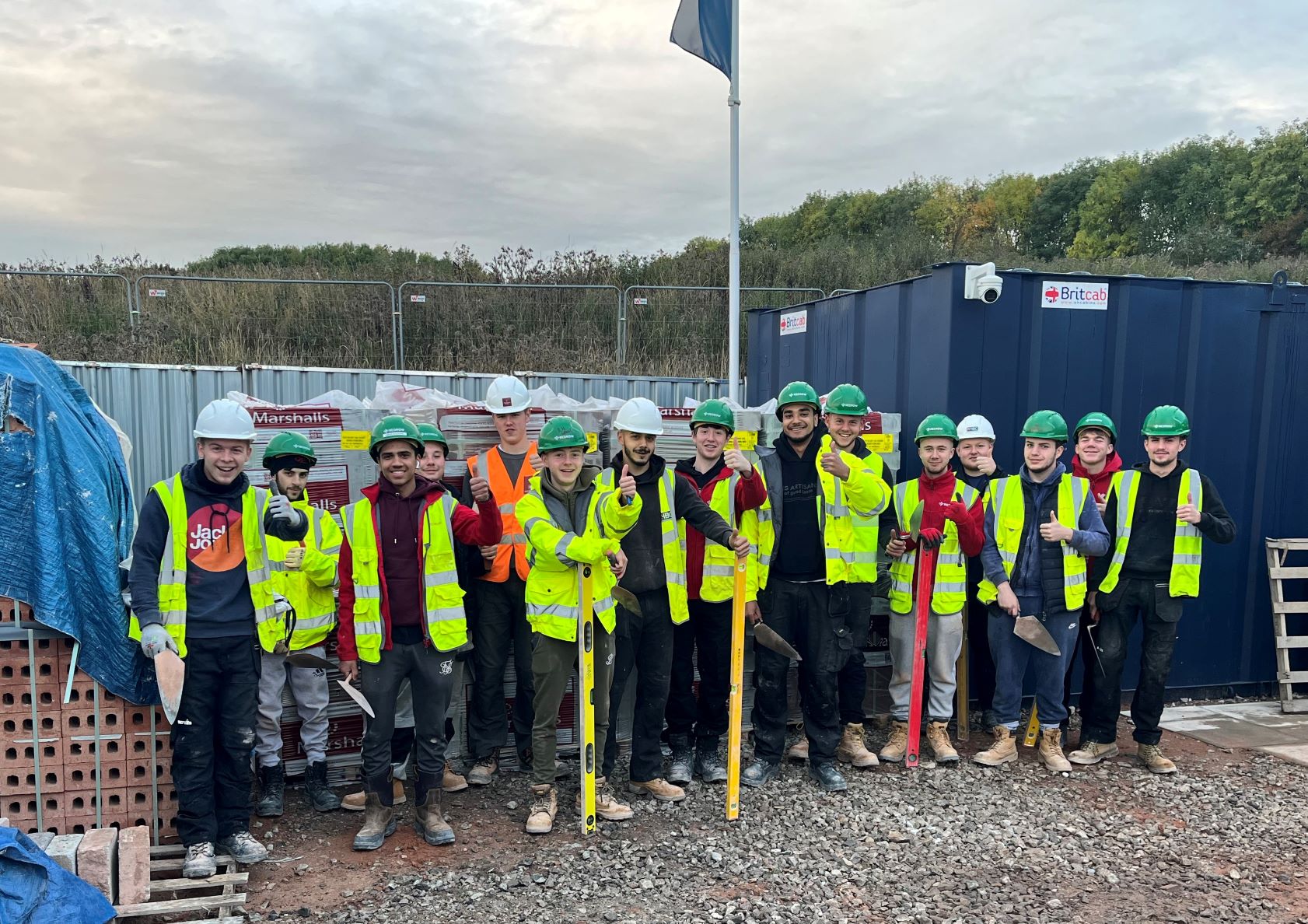 a group of apprentices in site safety clothing smiling at the camera