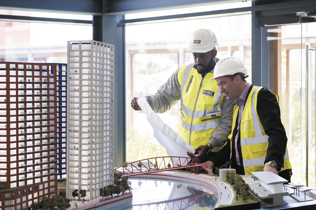 two people in site safety clothing looking at a model of a building
