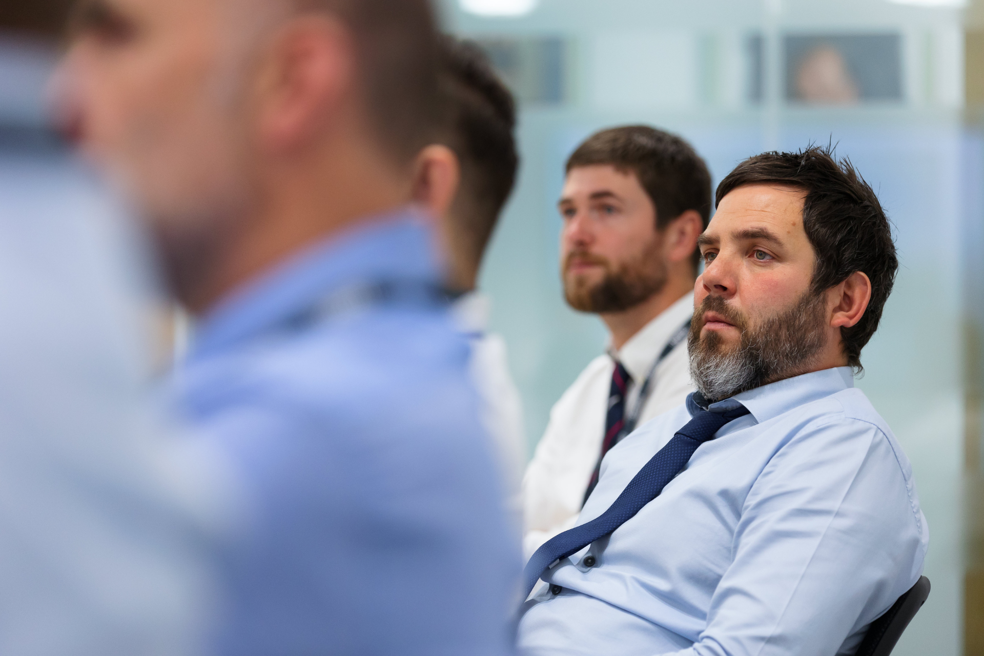 men in shirts and ties listening to a meeting