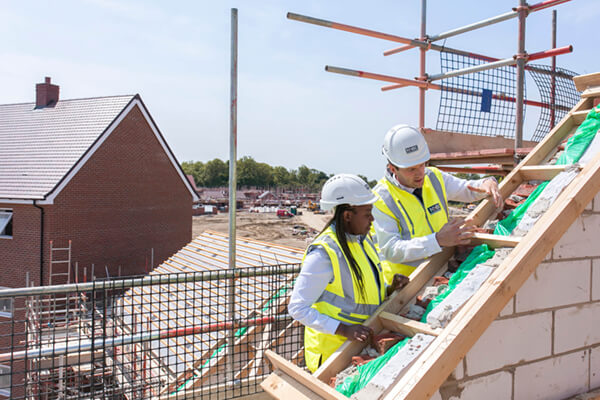 a photo of two people in site safety clothing checking some work completed on a roof frame