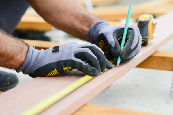 a photo of someone wearing gloves measuring a piece of wood