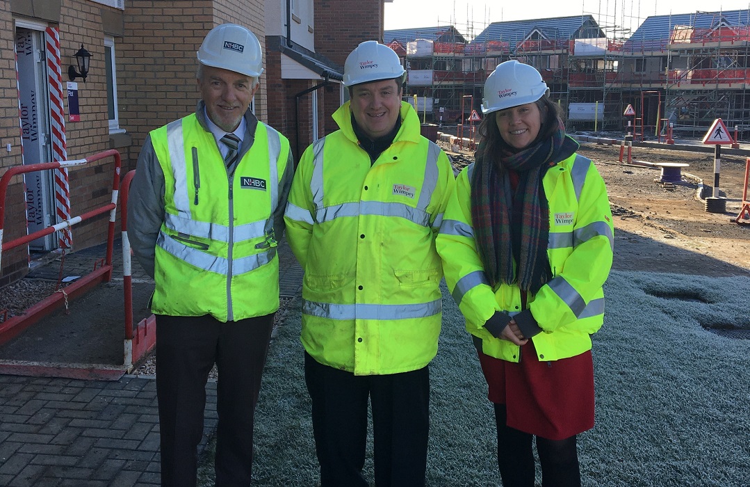 three people in site safety clothing and hard hats smiling at the camera
