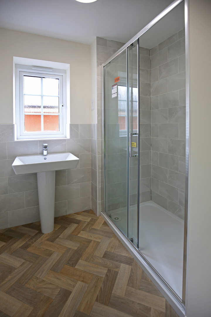 a modern bathroom with a white basin and a glass-door shower cubicle