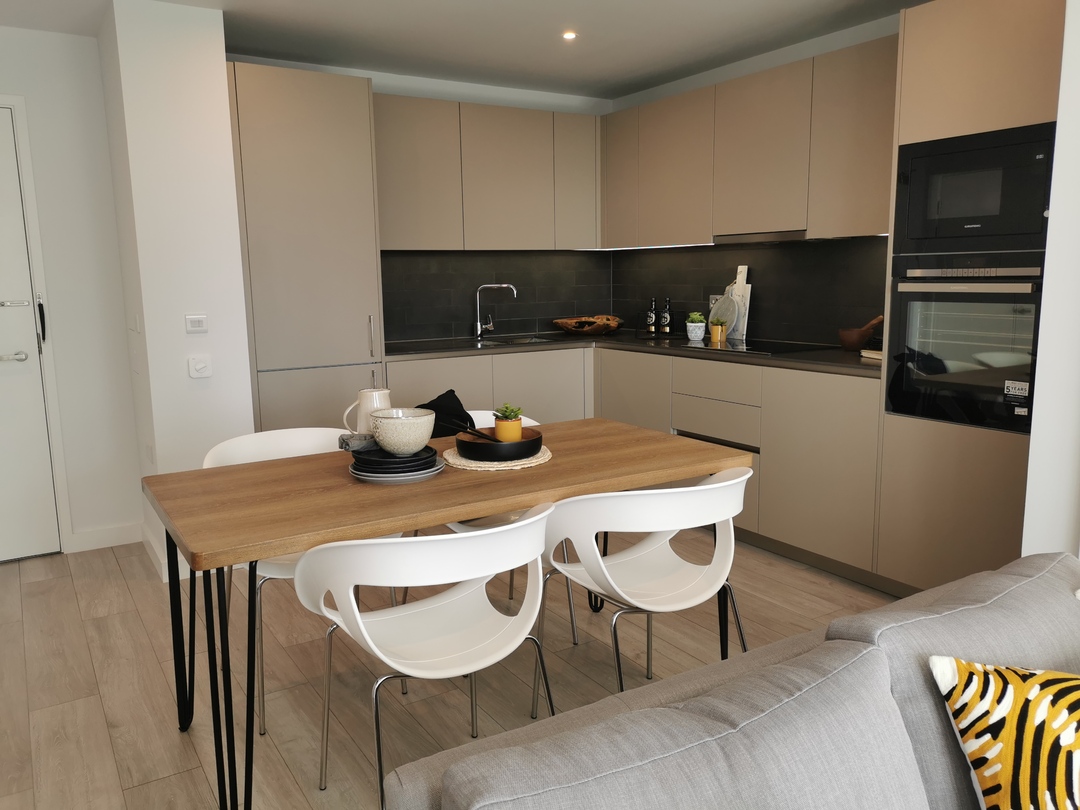 a modern looking beige kitchen with a woden and white dining table set