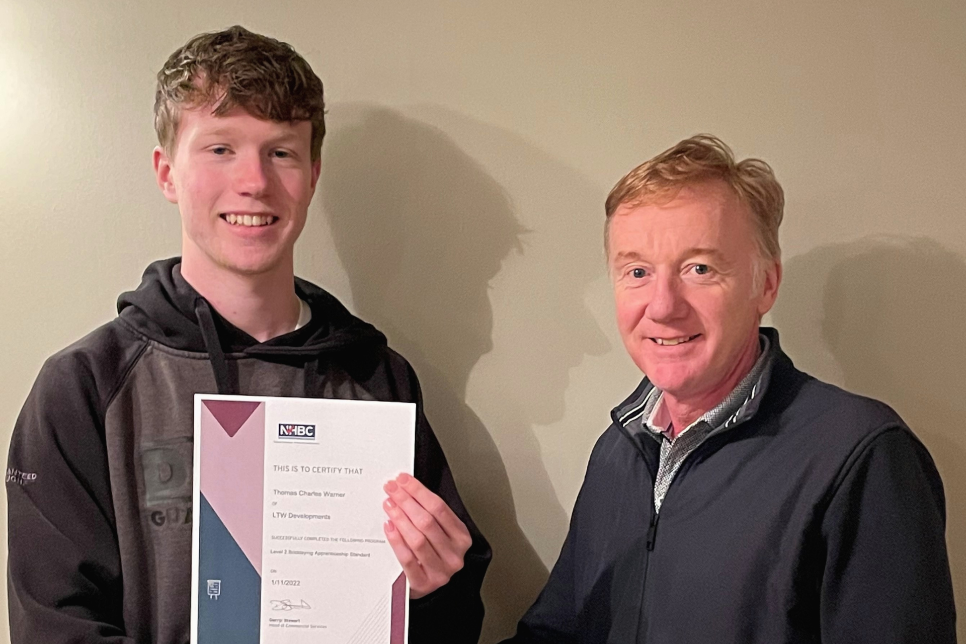 a photo of two people holding an apprenticeship certificate