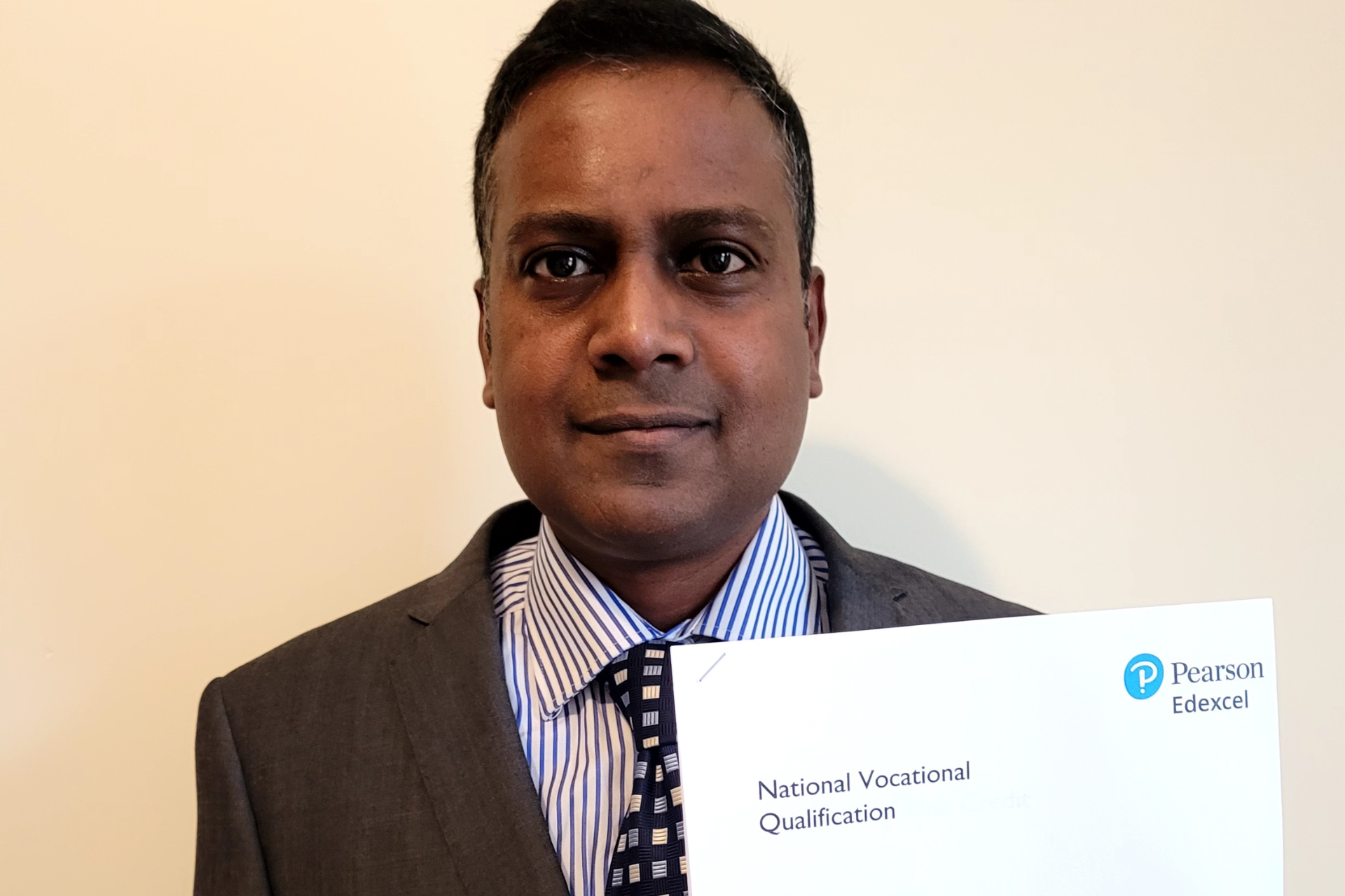 a photo of a man in a suit holding a certificate looking into the camera