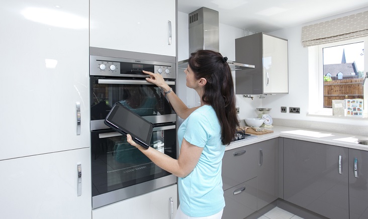 a woman in a blue shirt holding a tablet inspecting her new oven