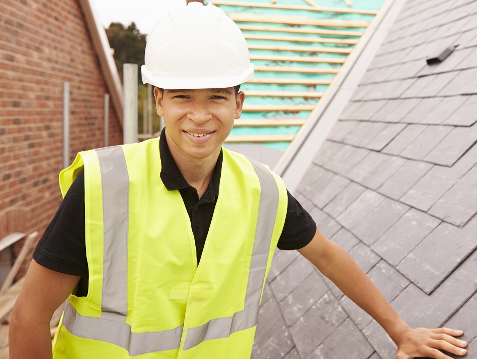 young man in site safety clothing and a hard hat smiling at the camera