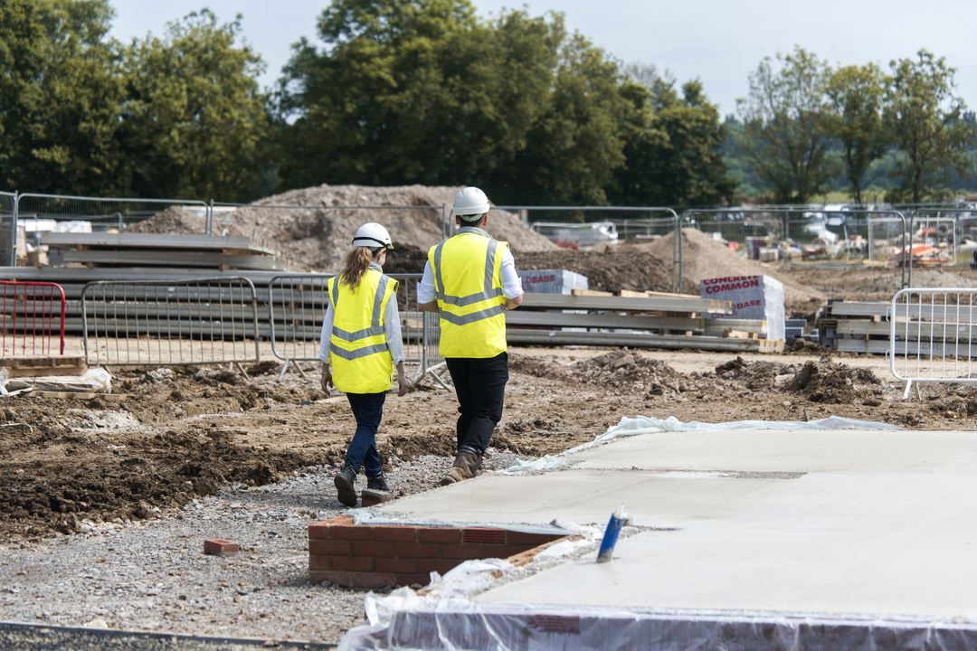 two people walking on site in site safety clothing and hard hats
