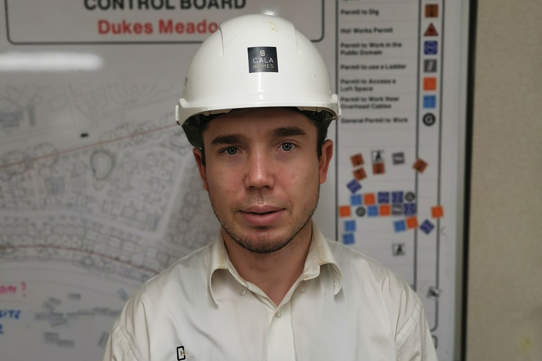 a man in a white shirt and white hard hat looking at the camera