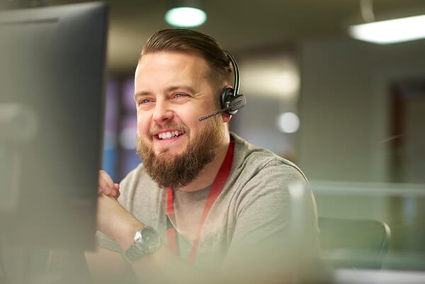 a man wearing a headset sat at a desk smiling