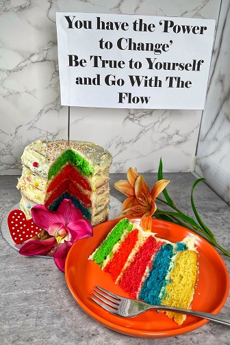 a picture of a rainbow layered cake with a sign above it
